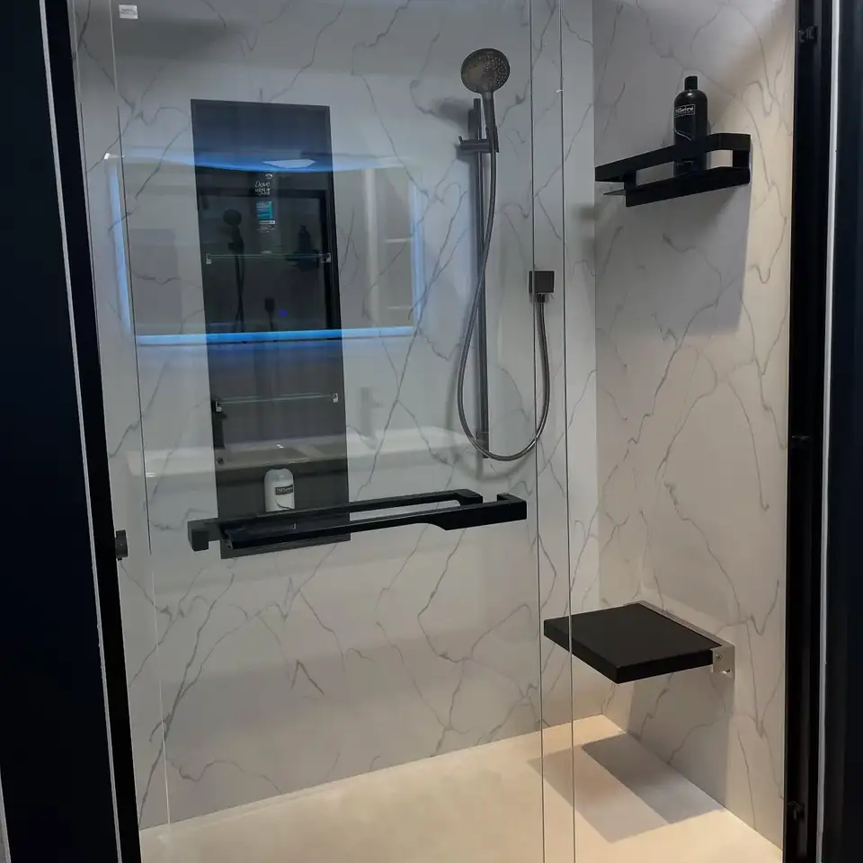 Bathroom remodeling Boardman OH: walk-in shower with white marble-look solid surface walls, black fixtures, fold-down seat and glass door